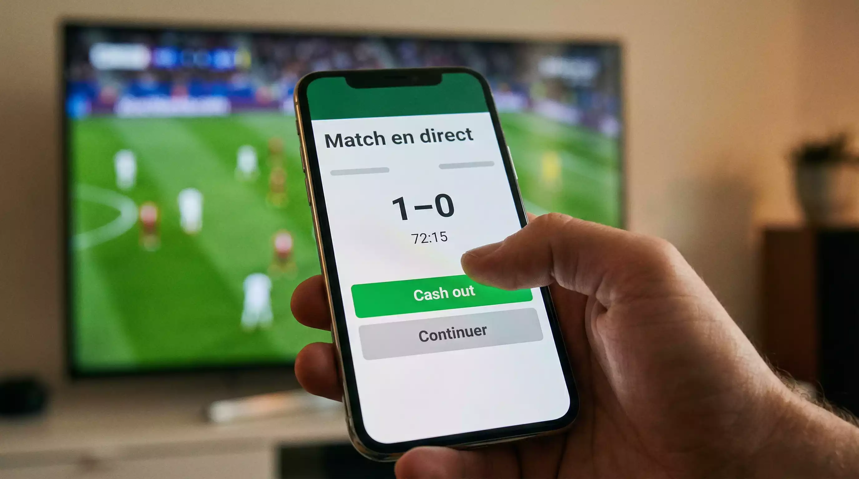 Main d'un homme appuyant sur un bouton lumineux vert sur l'écran d'un smartphone pendant un match de football