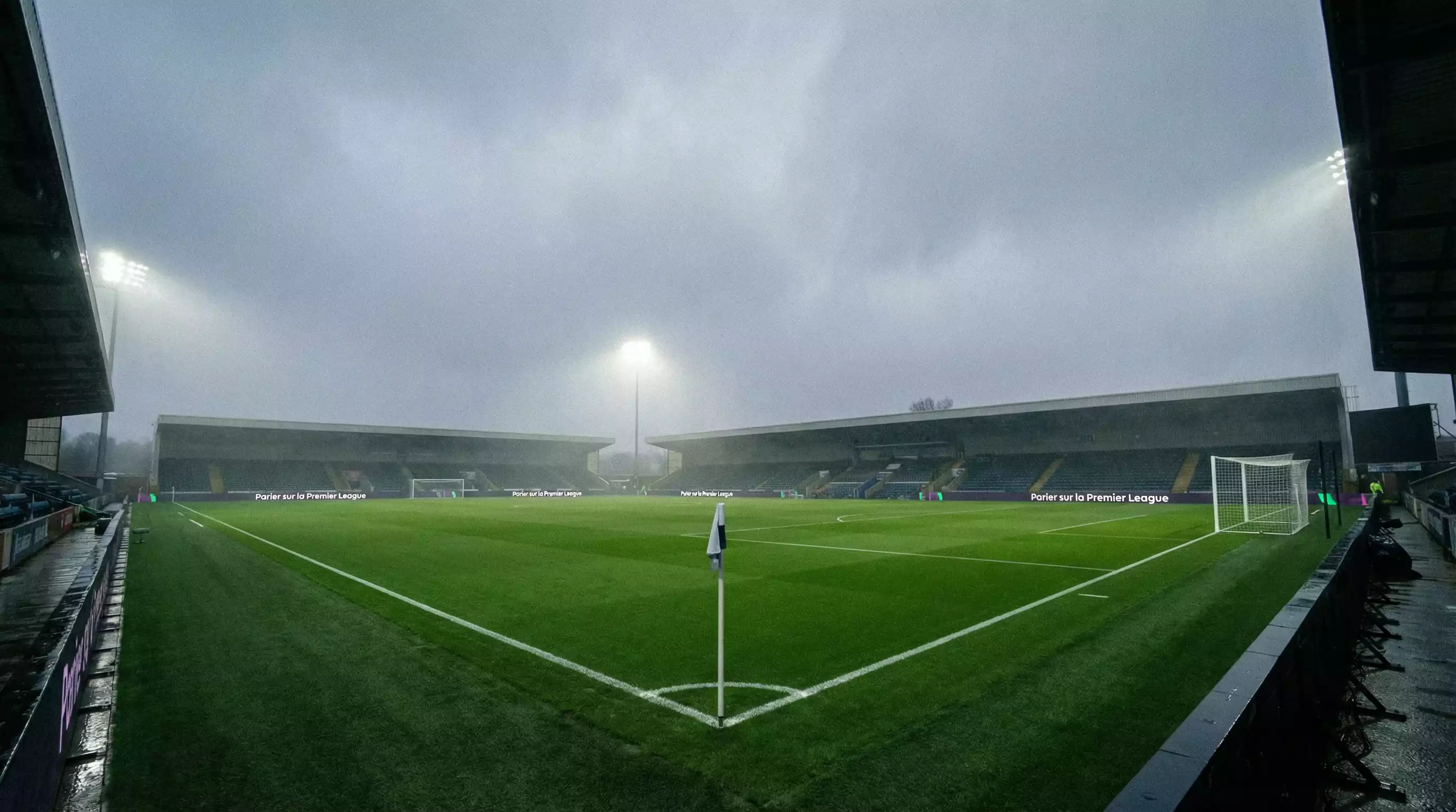 Terrain de football anglais vu depuis le virage d'un stade avec une pelouse verte intense sous un ciel couvert